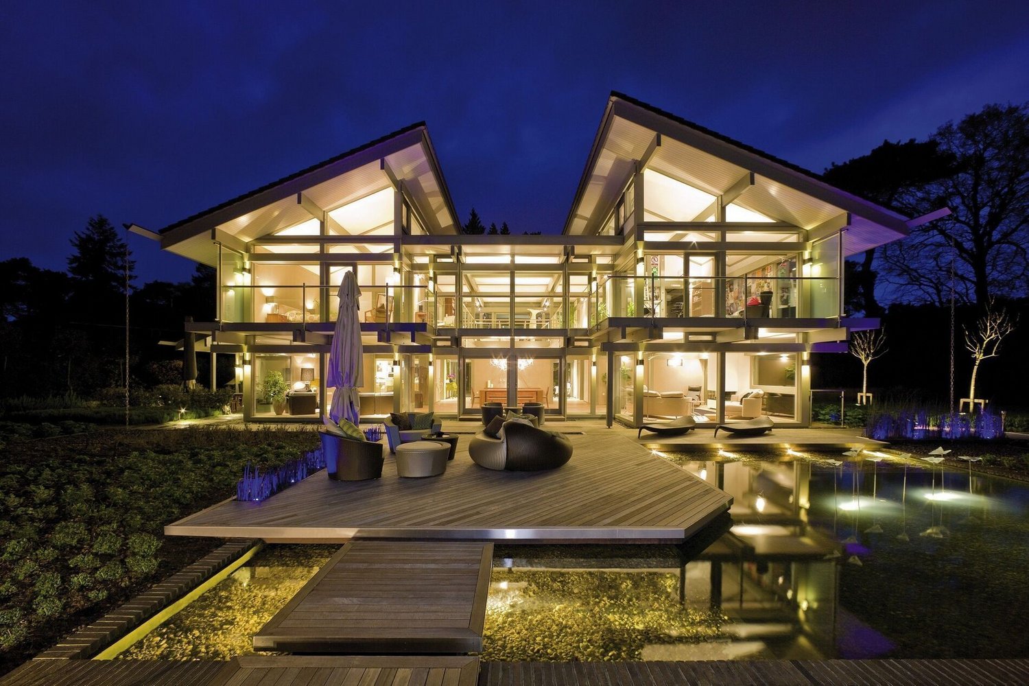 Modernes Einfamilienhaus in Holz-Glas-Architektur Helles modernes Haus mit großzügigem Garten und Wasserfläche bei Nacht