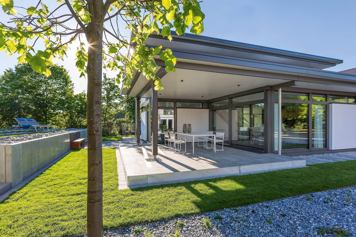 Moderne Architektur eines Wohnhauses mit Terrasse Geräumige Terrasse mit Garten und moderner Bauweise