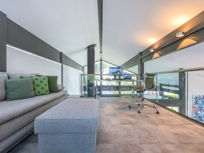 Heller Wohnraum mit Sofa, Schreibtisch und großen Fenstern