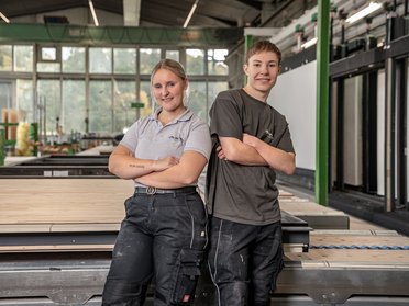 Junge Handwerker in einer Werkstatt mit Holz Zwei junge Handwerker posieren in einer modernen Werkstatt.