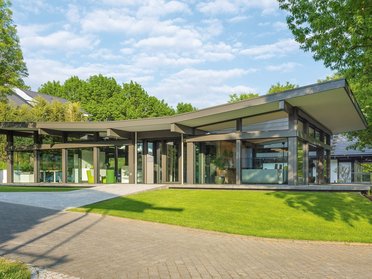 Helles, elegantes Haus umgeben von grünem Garten und Bäumen