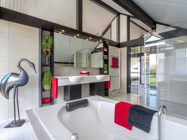 Helles Badezimmer mit Wanne, Spiegeln und stilvollen Dekorationen