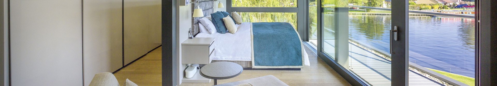 Elegantes Schlafzimmer mit großen Fenstern und Wasseraussicht