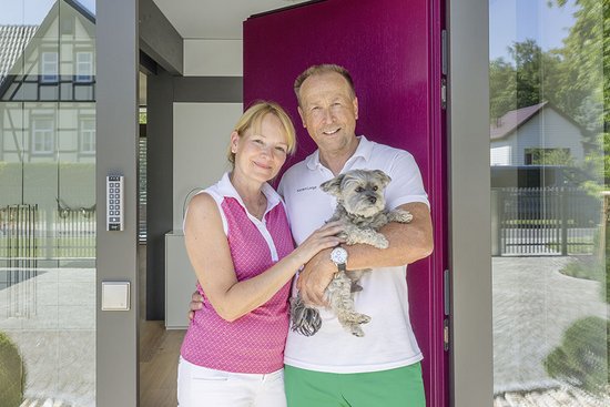 Modernes Architektenhaus mit gemütlichem Design und Garten Paar steht vor dem Eingang eines modernen Hauses mit Hund