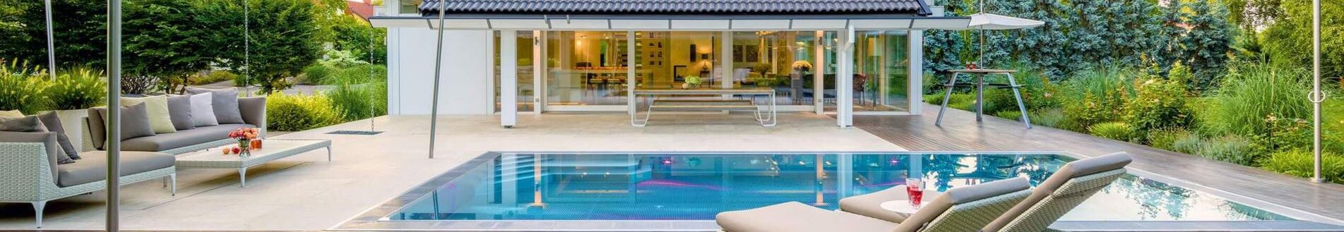 Weißes Fachwerkhaus mit Doppelpultdach, Pool und großzügiger Terrasse.