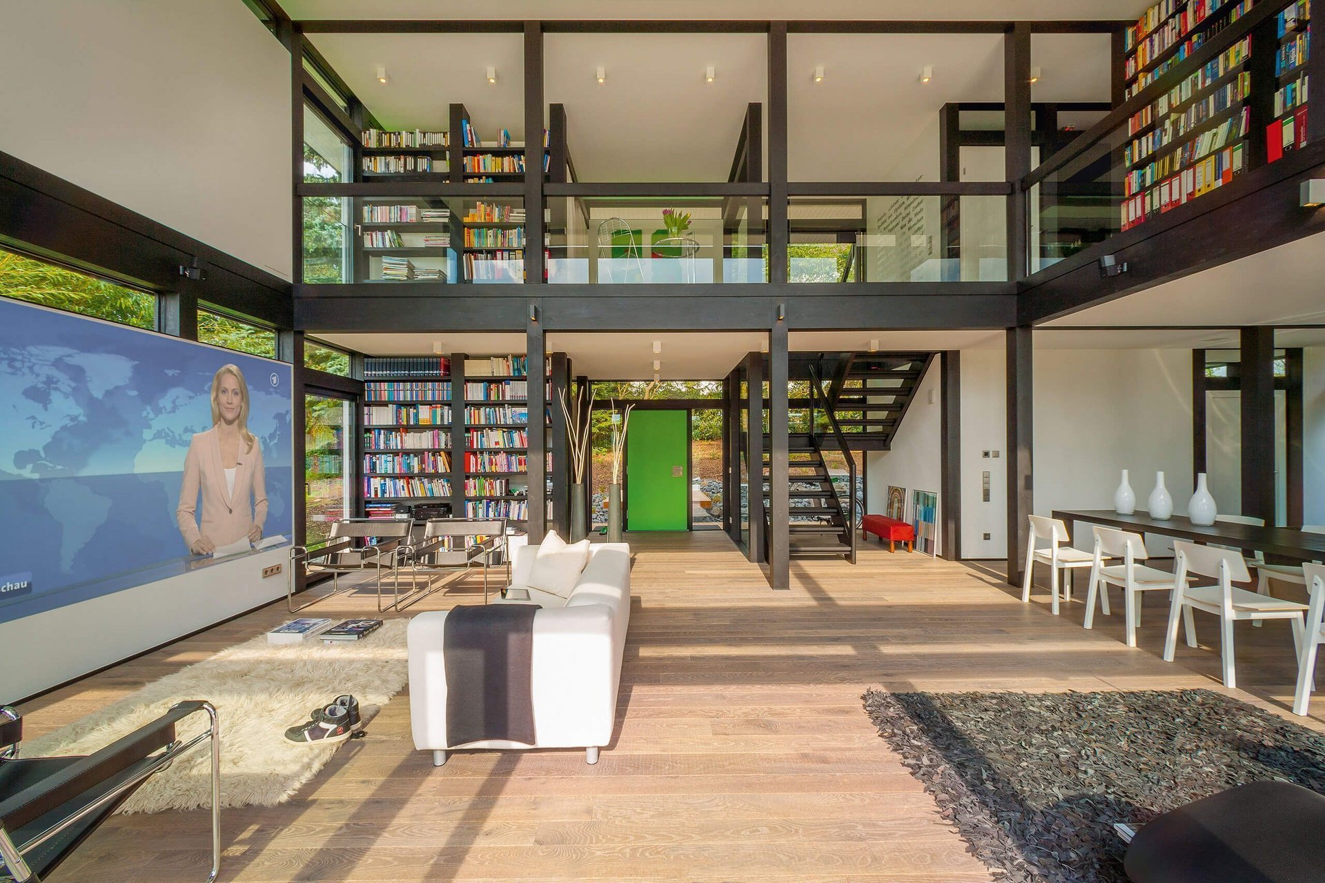 Helles, modernes Wohnzimmer mit großer Fensterfront und Bibliothek