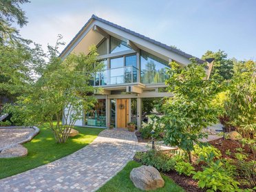 Modernes HUF Haus mit Giebel, Poolhaus und Garagenanlage in grünem Umfeld