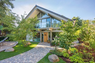 Modernes HUF Haus mit Giebel, Poolhaus und Garagenanlage in grünem Umfeld