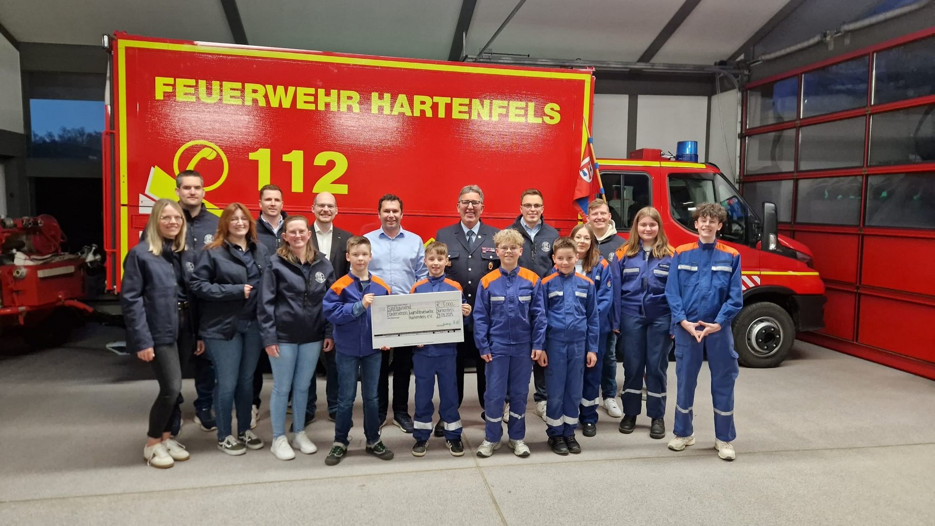 Gruppenbild der Feuerwehr Hartenfels mit Scheck in der Feuerwache