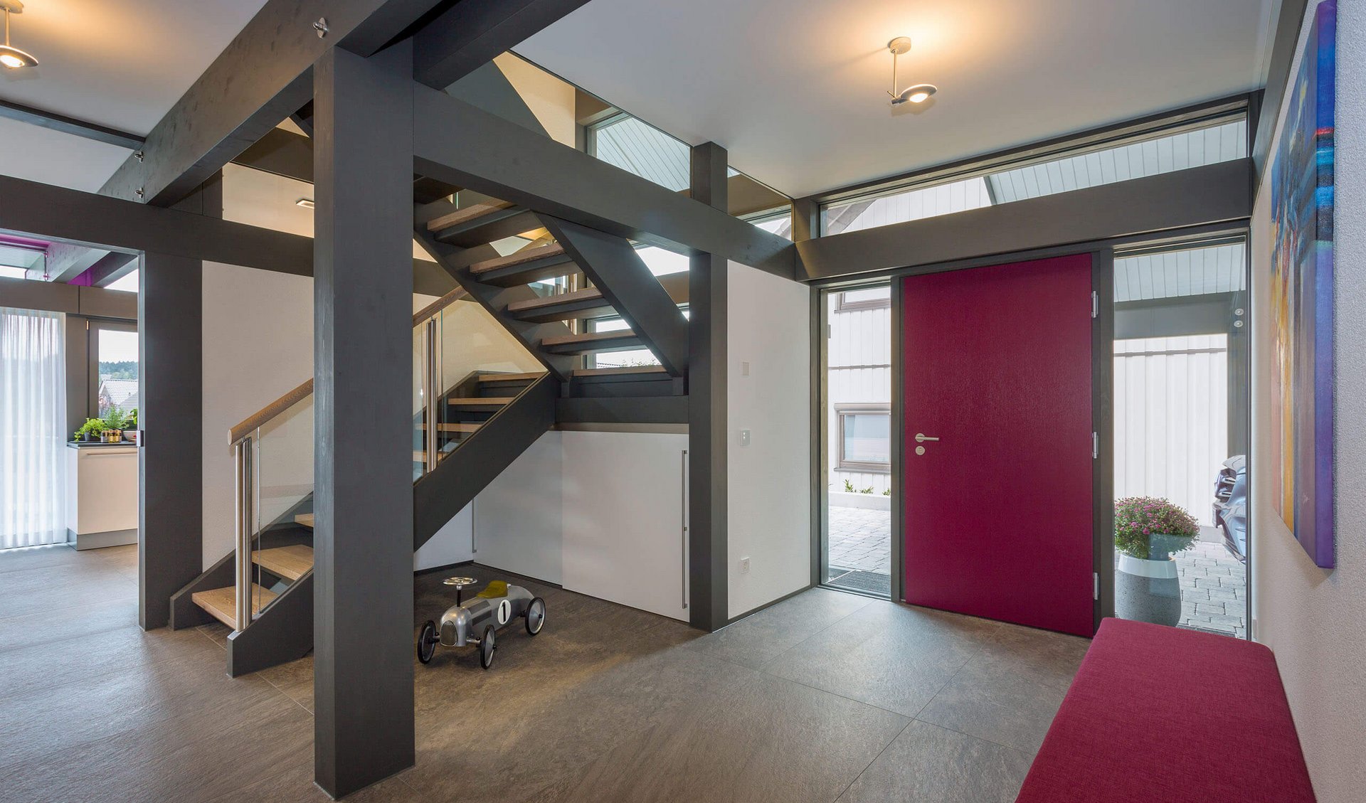 Moderne Flureingang mit Treppe und roter Tür Ein heller Flur mit moderner Treppe und roter Eingangstür