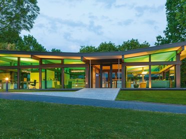 Zeitgenössisches Gebäude mit großen Fenstern und Gartenlandschaft
