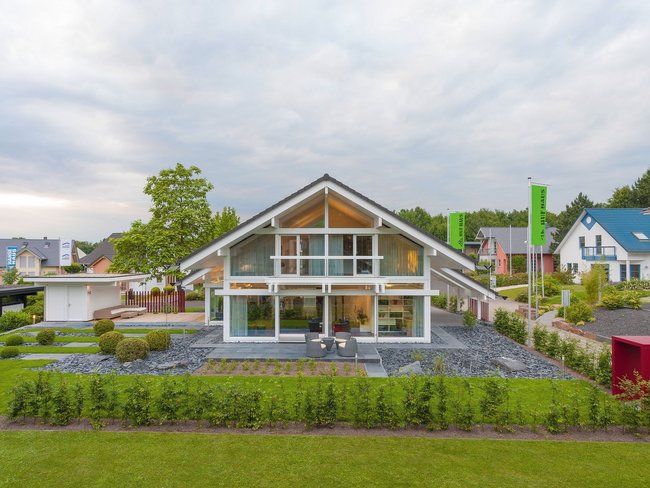 HUF Musterhaus Frankfurt weiss 40 Ein modernes Haus mit großen Fenstern und gepflegtem Garten.