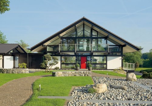 Moderne Villa mit großer Glasfront und roter Tür Architektur einer modernen Villa mit Garten und Steinen
