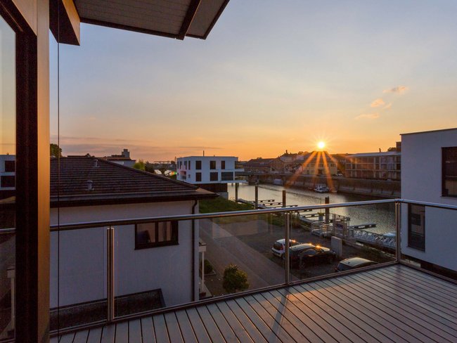 Bestandshaus mit HUF Aufstockung Balkonblick auf Bestandshaus mit Sonnenuntergang und Wasserblick
