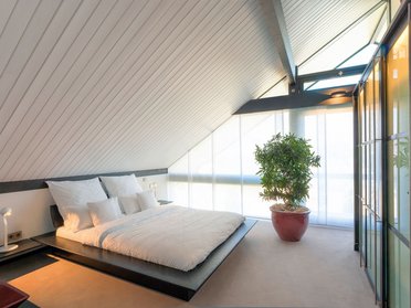 Ein stilvolles Schlafzimmer im Dachgeschoss mit minimalistischer Einrichtung