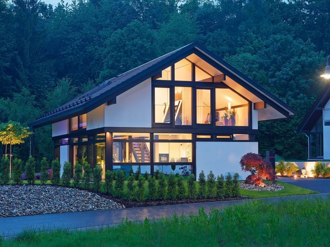 Stilvolles Familienhaus mit architektonischem Design Gemütliches Architektenhaus umgeben von grüner Landschaft bei Nacht