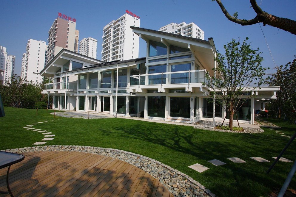Modern villa with large garden and surrounding buildings Contemporary house with large windows and green lawn