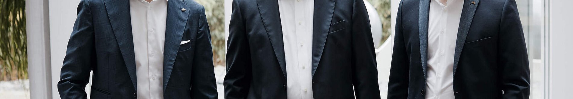 Drei Männer posieren für ein Foto in einem modernen Bürogebäude