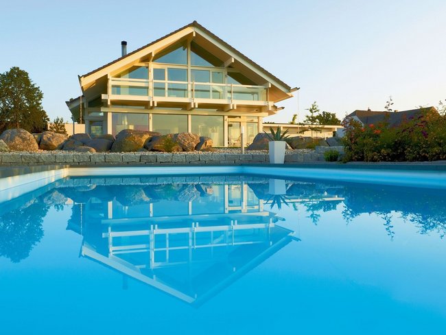 Moderne Architektur eines HUF HAUS mit einem blauen Pool im Vordergrund