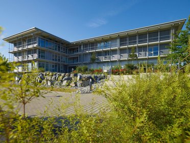 Bürogebäude HUF bei klarem Himmel Moderne Architektur des Bürogebäudes HUF mit Pflanzen und Steinmauer im Vordergrund