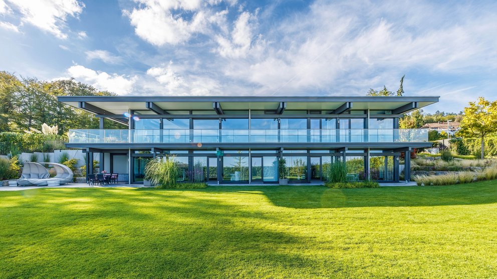 Moderne Architektur des HUF HAUS mit großzügigen Glasfronten und grünem Garten