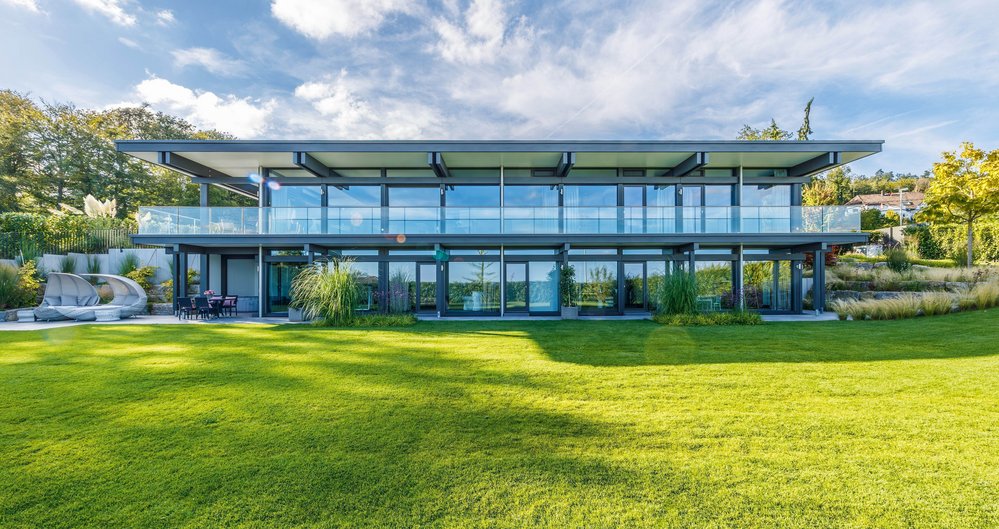 Moderne Architektur des HUF HAUS mit großzügigen Glasfronten und grünem Garten