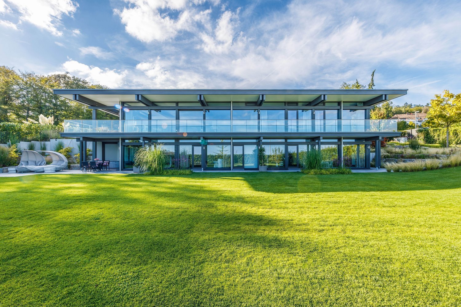 Maximale Transparenz im HUF HAUS mit Flachdach Moderne Architektur des HUF HAUS mit großzügigen Glasfronten und grünem Garten