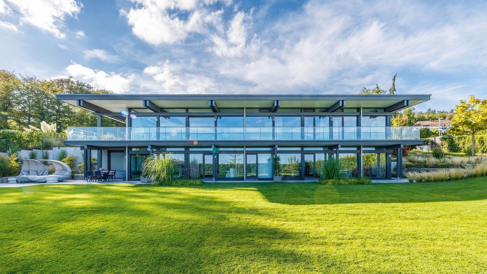 Moderne Architektur des HUF HAUS mit großzügigen Glasfronten und grünem Garten