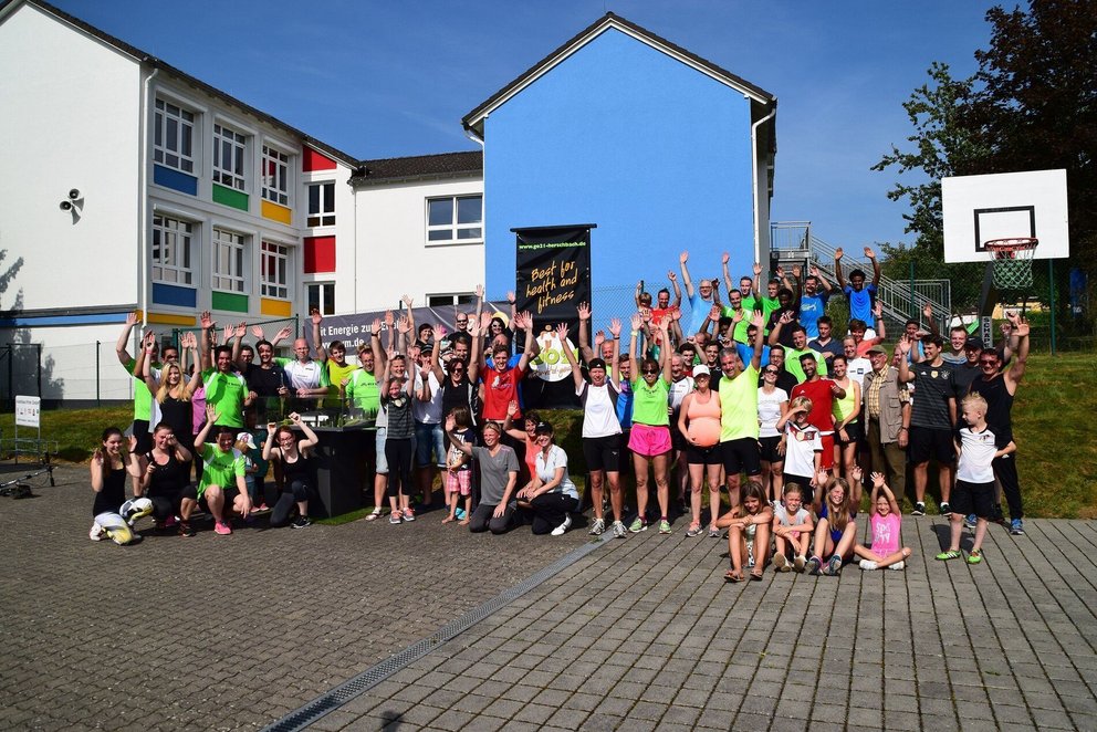 Gruppenfoto von Läufern vor einem Schulgebäude Menschen versammeln sich für ein Gruppenfoto im Freien
