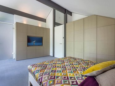 Helles Schlafzimmer mit TV und geometrischem Bettüberwurf