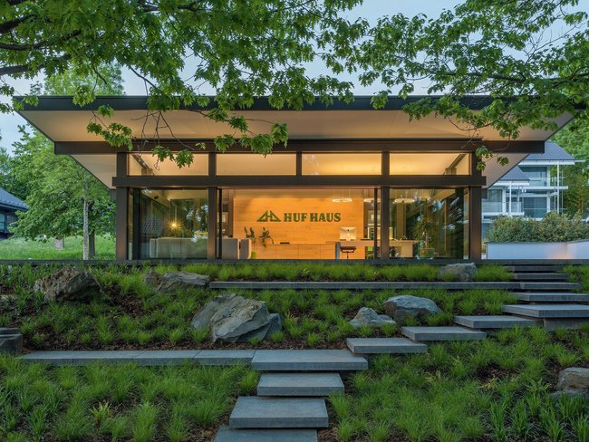 HUF HAUS mit Glasfassade und begrüntem Gelände im Vordergrund