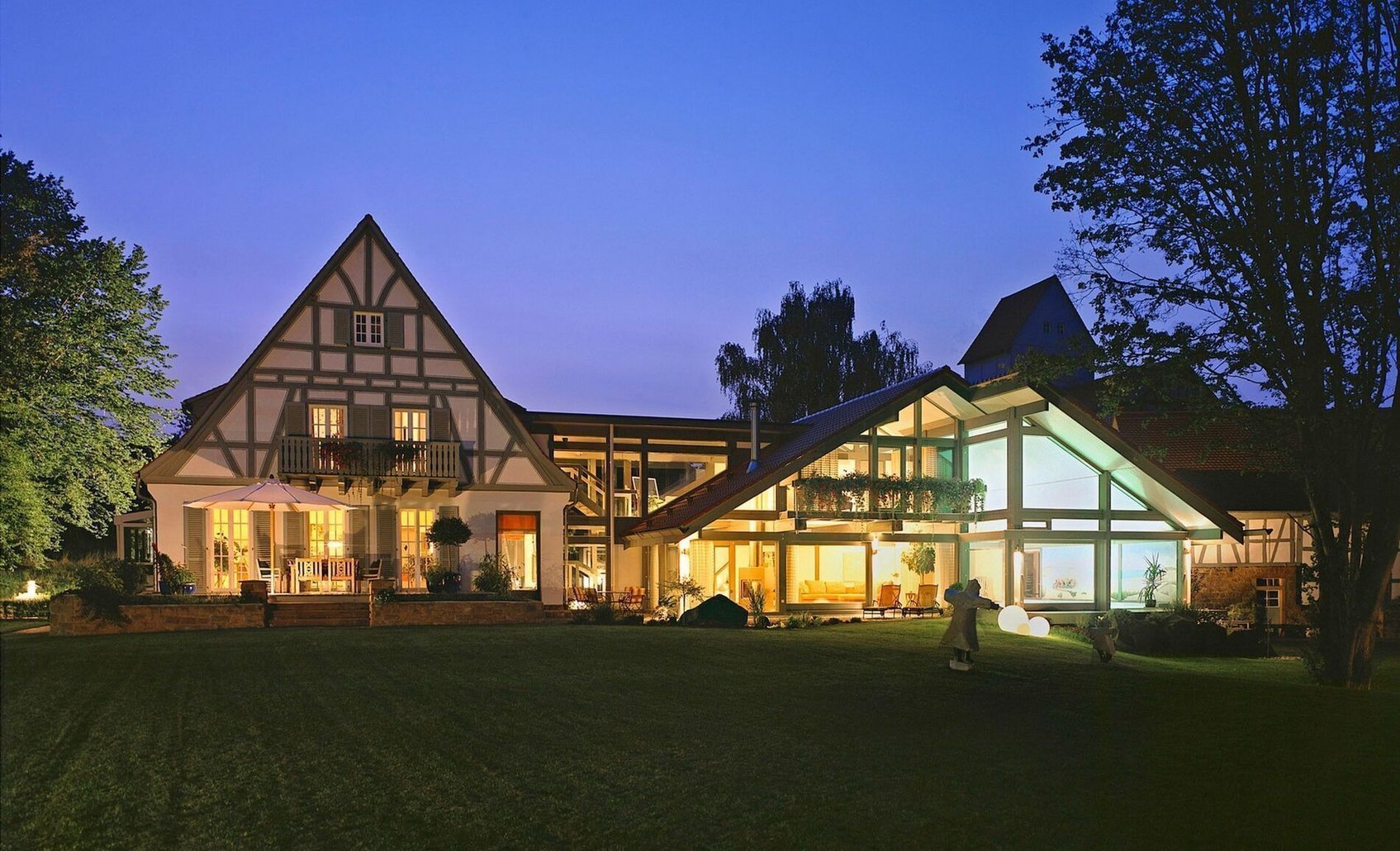 Moderne Hausarchitektur mit individuellem Anbau Ansicht eines Hauses mit gut beleuchtetem Anbau bei Dämmerung