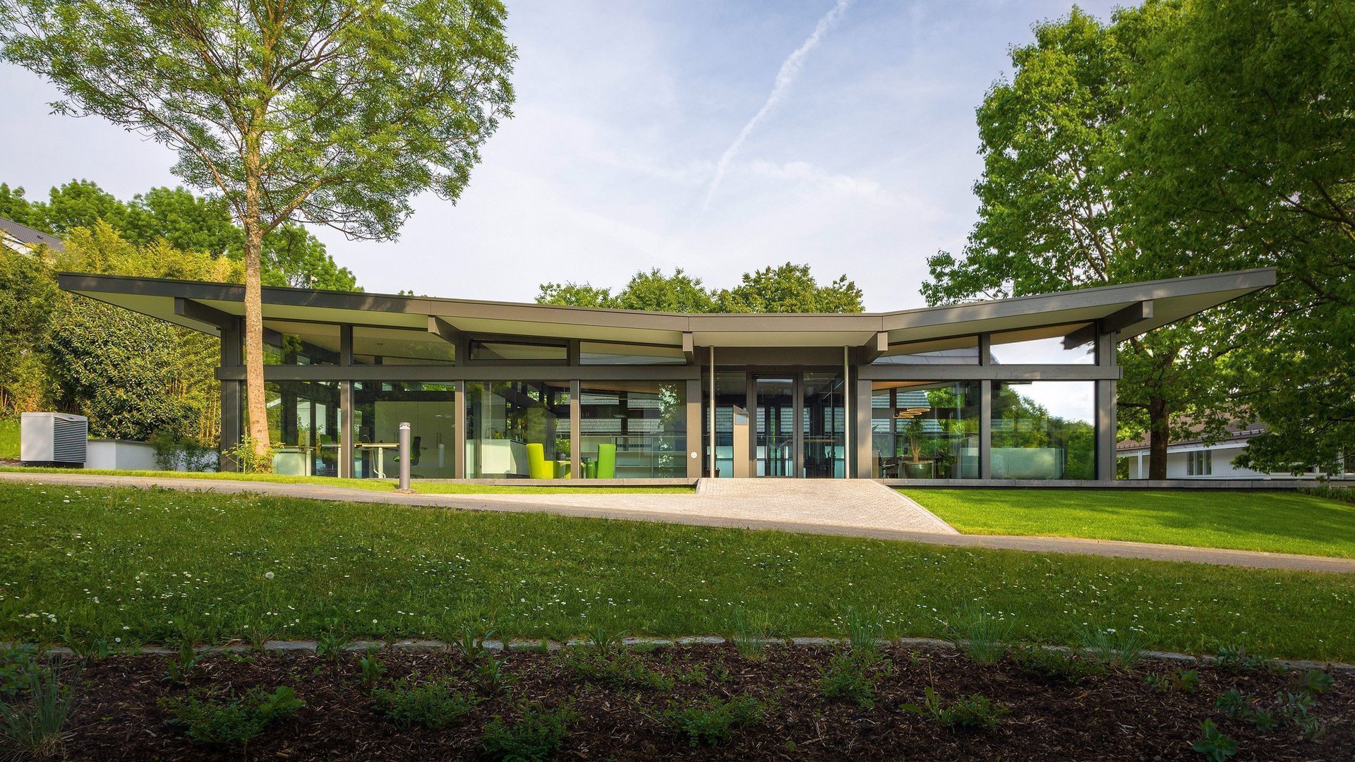 Moderne Architektur eines Gebäudes in einer Parklandschaft Ansicht eines modernen Gebäudes umgeben von Bäumen und Rasenflächen