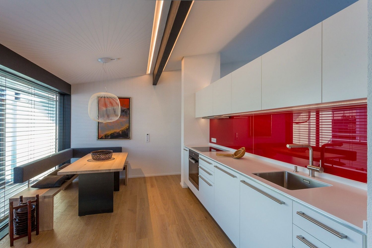 Moderne Küche im HUF Bürogebäude mit roter Wand Stilvolle Küche mit Holzfußboden und minimalistischer Einrichtung
