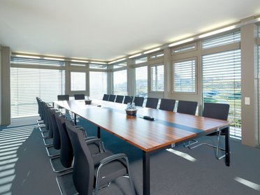 Modernes Bürogebäude mit Konferenzraum Heller Konferenzraum mit großem Tisch und Stühlen, Fenster mit Jalousien