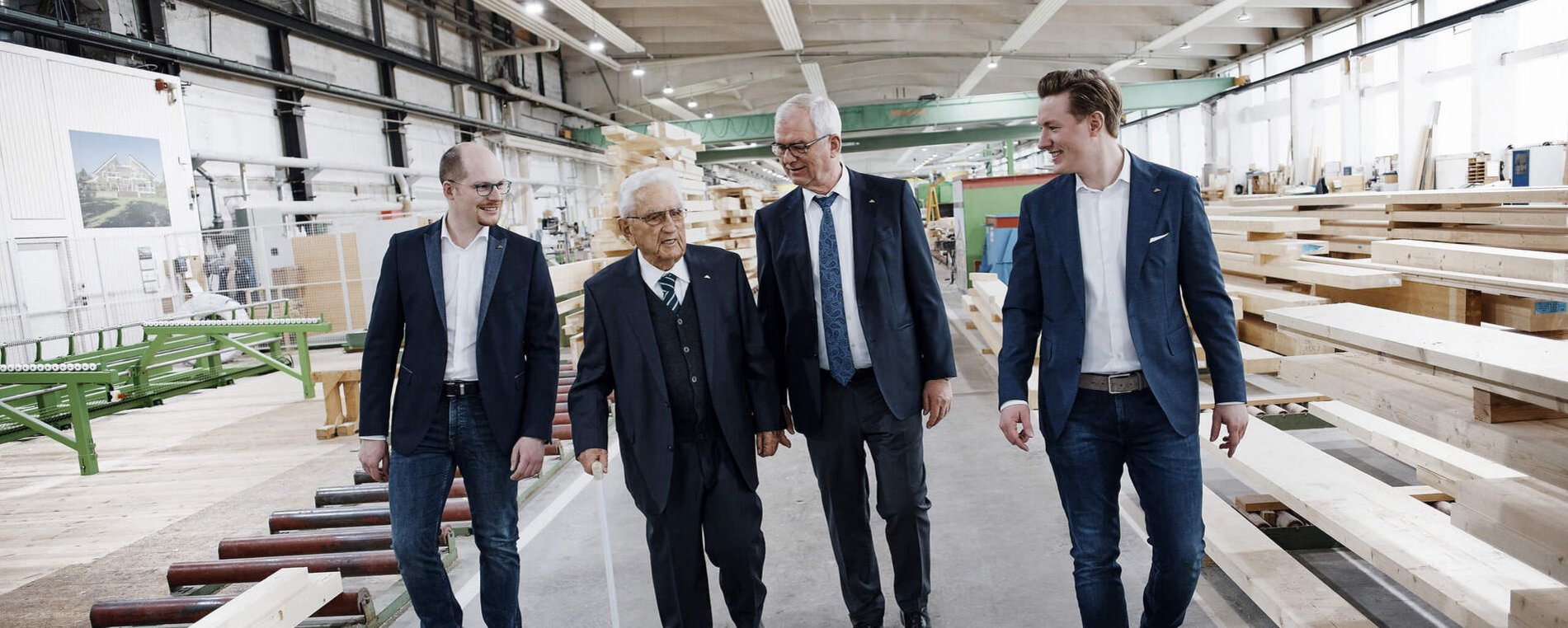 Vier Männer gehen durch eine Holzverarbeitungshalle
