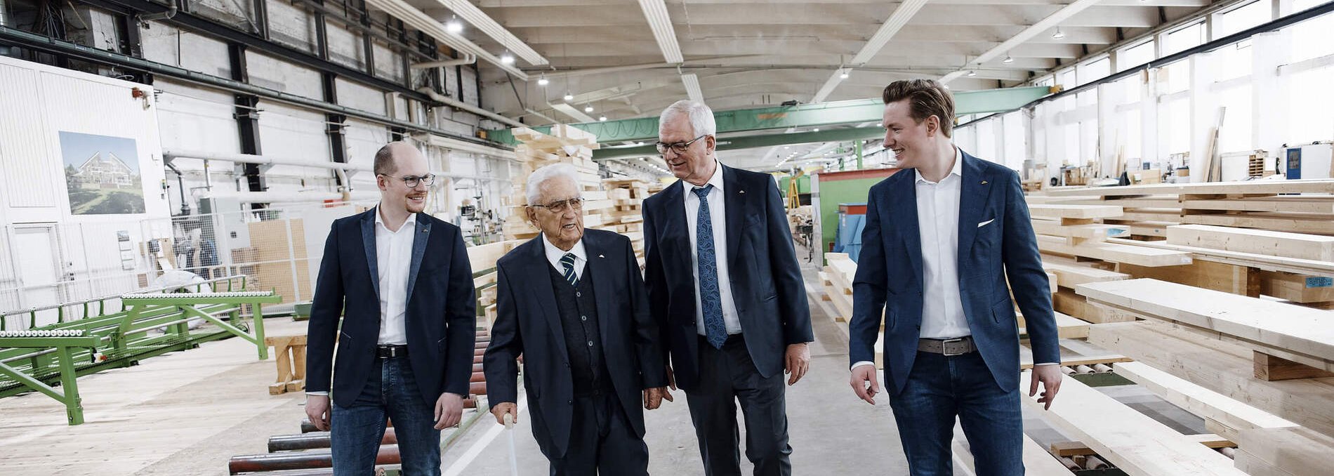 Besuch in einer Holzverarbeitungshalle Vier Männer gehen durch eine Holzverarbeitungshalle