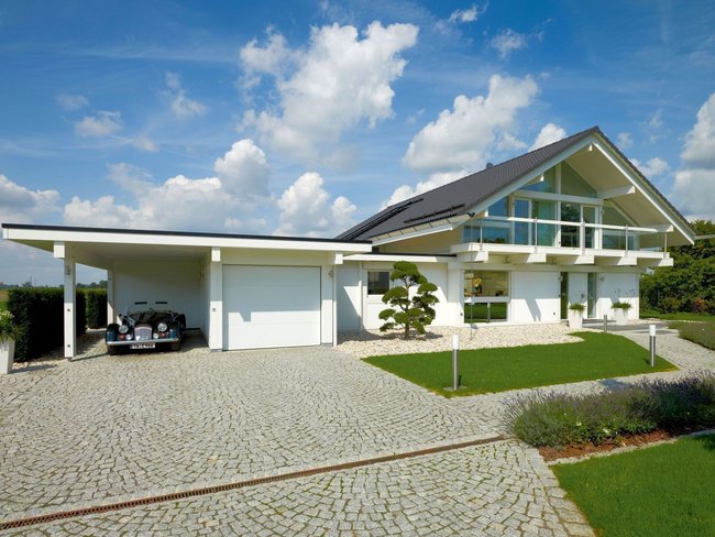 Fachwerkhaus mit Carport und grüner Umgebung unter blauem Himmel