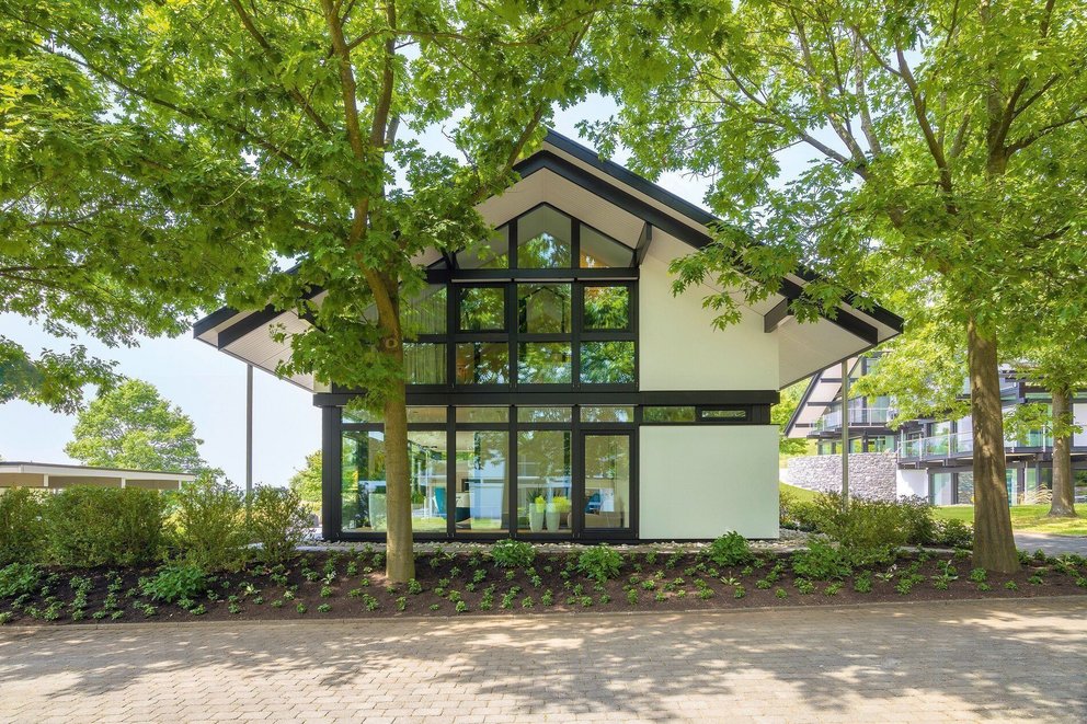 Moderne Architektur umgeben von Bäumen Ein zeitgenössisches Gebäude mit großen Fenstern in einer grünen Umgebung