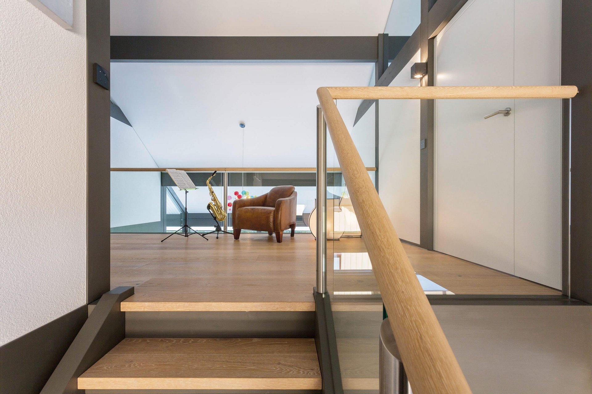 Moderne Innenansicht eines Wohnraums mit Musikinstrument Heller Wohnraum mit Treppe, Sofa und Saxophon-Ständer