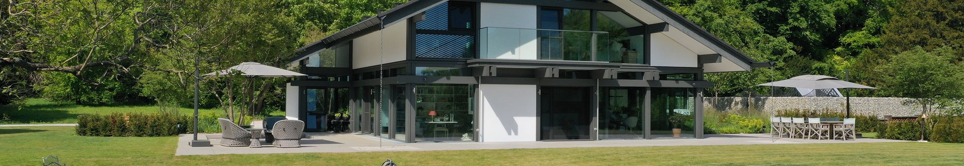 Helles, modernes Haus umgeben von Bäumen und einem Teich
