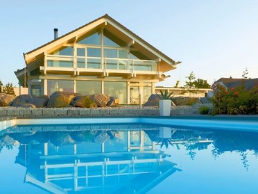 Modernes Fachwerkhaus mit Pool und Gartenlandschaft im Hintergrund