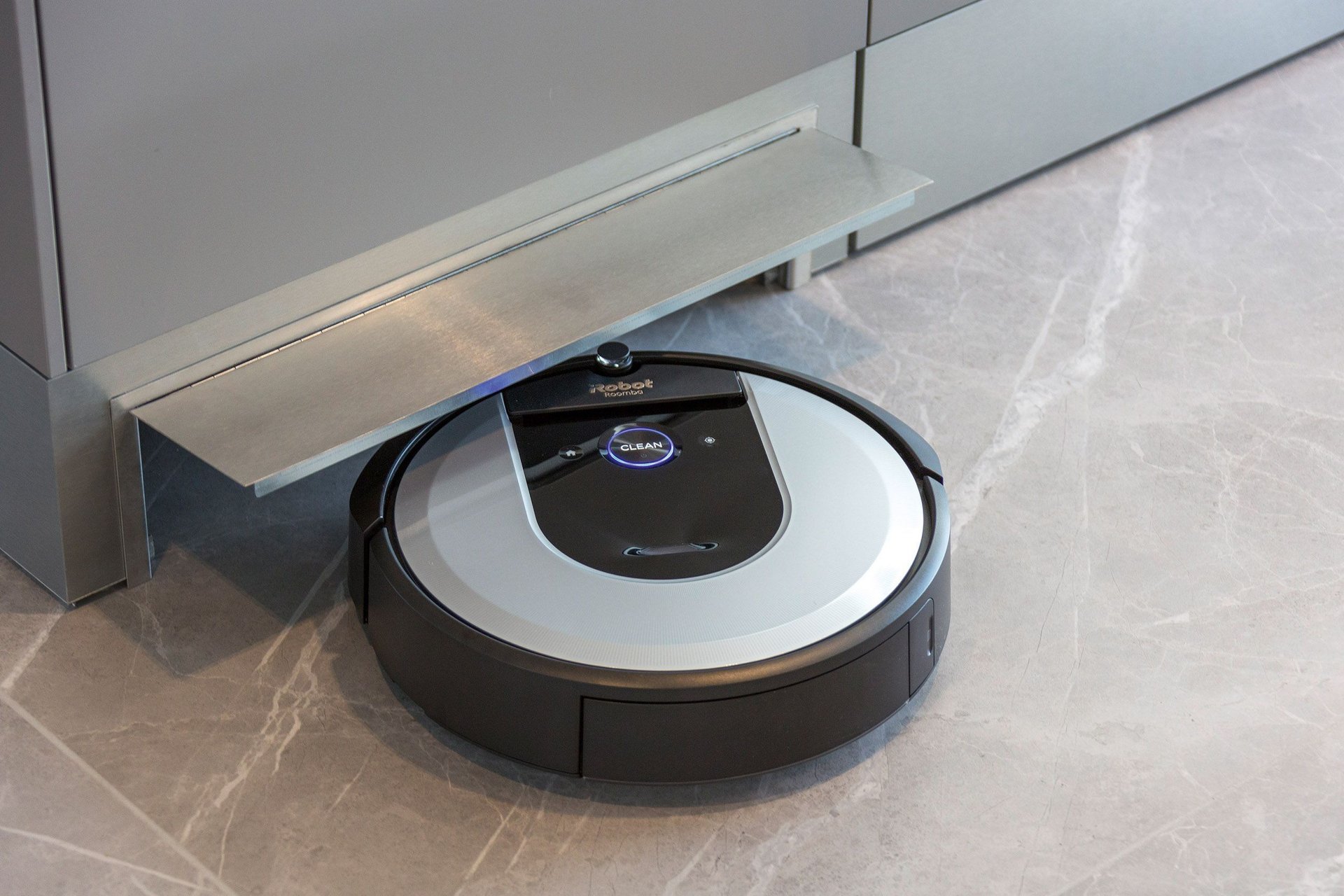 Ein Roboterstaubsauger ruht unter einer Küchenzeile auf einem modernen Boden