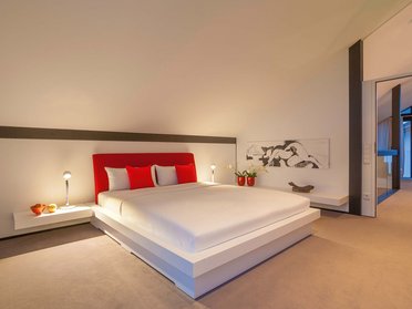 Elegantes Schlafzimmer mit rotem Bett und minimalistischer Dekoration