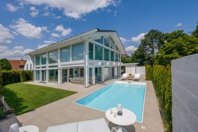 Außenansicht eines modernen HUF Hauses mit Schwimmbad und grünem Garten