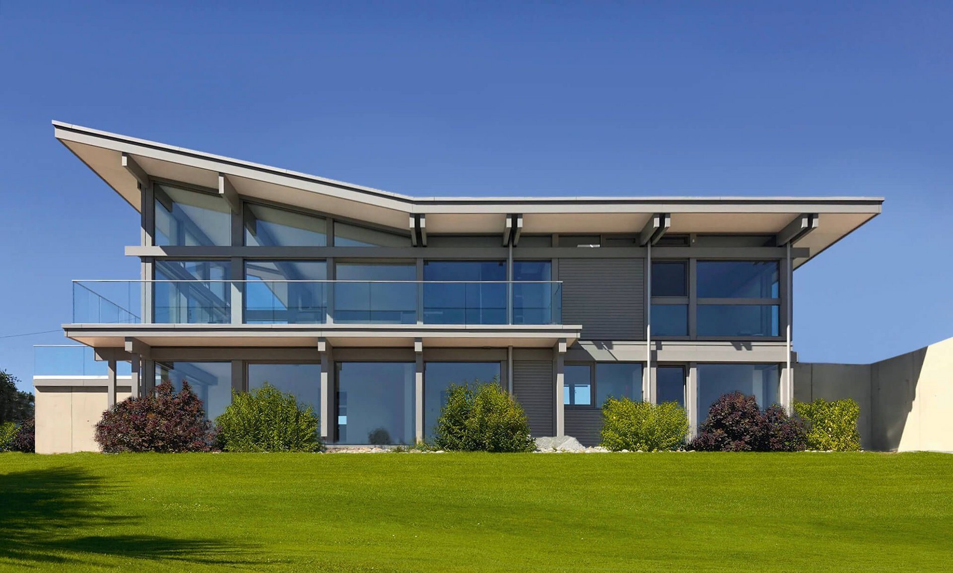 Ein stilvolles modernes Haus mit Glasfenstern und Pflegerasen.