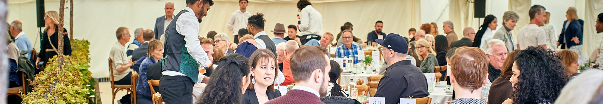 Guests enjoying a meal at round tables in a large tent