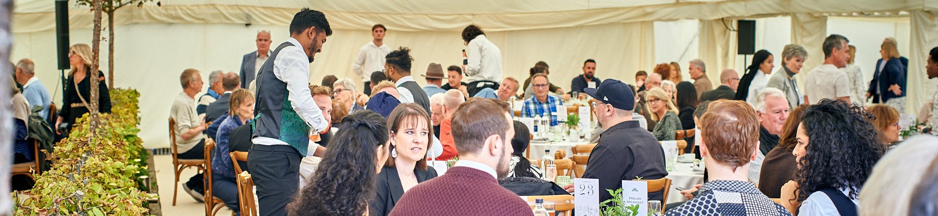 Guests enjoying a meal at round tables in a large tent