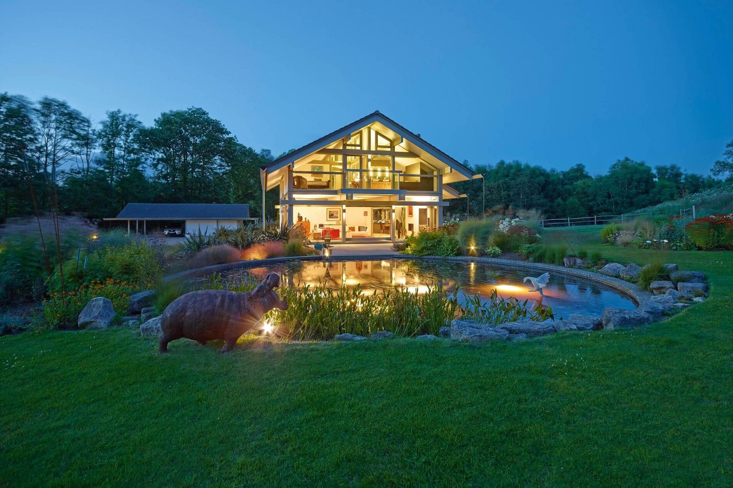 HUF Haus ART 3 mit Garten im Einklang mit der Natur Designhaus mit Garten und Wasserstelle bei Abendlicht