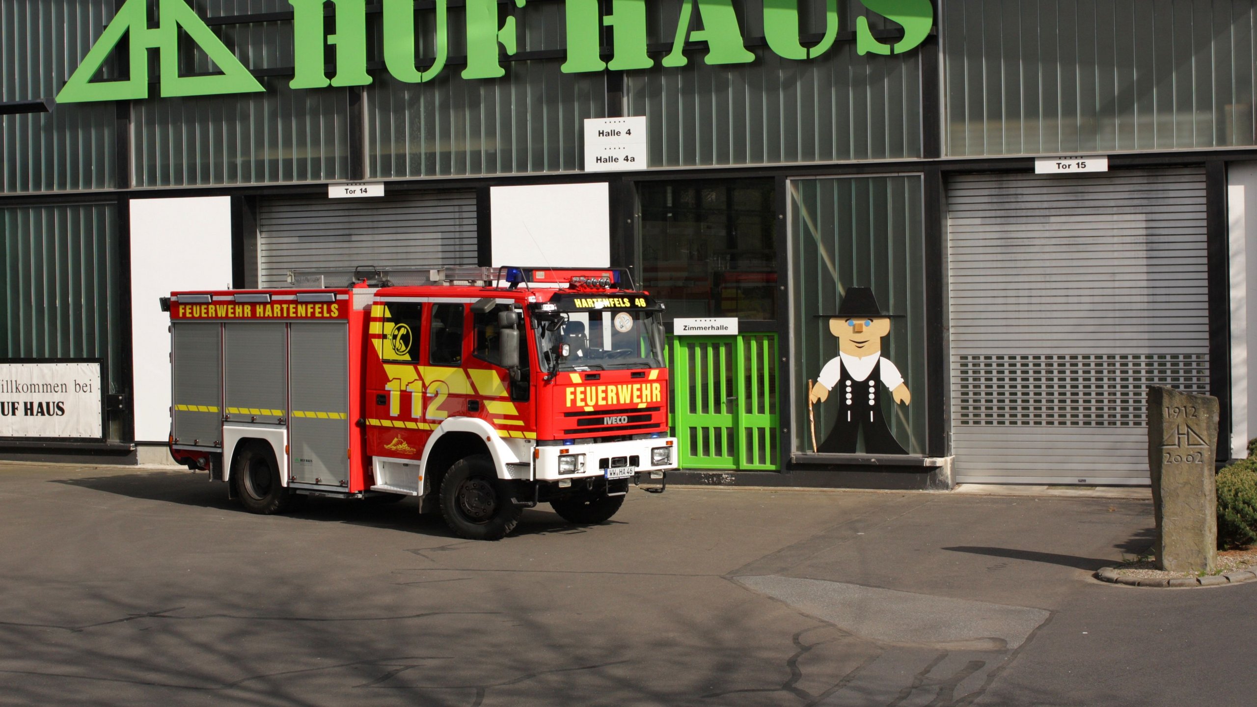 Feuerwehrfahrzeug vor HUF HAUS Gebäude Rotes Feuerwehrfahrzeug steht vor HUF HAUS mit grüner Fassade